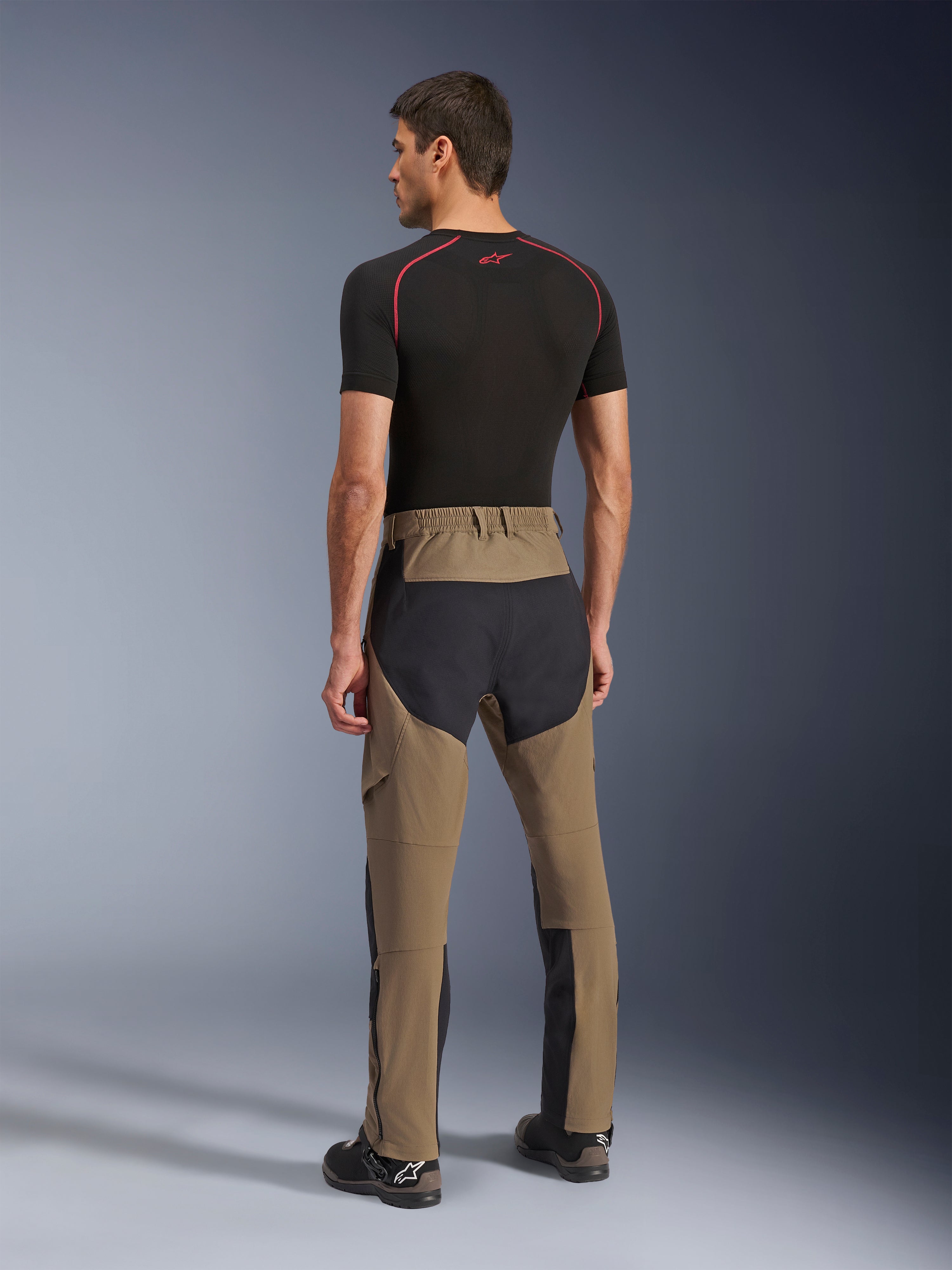 Alpinestars Flex-AST Explorer Hose, Adventure-Motorradhose, Walnut Black, Rückansicht am Modell mit schwarzen Ripstop-Einsätzen an Gesäß und Beinen, Stretch-Textilkonstruktion und lange Reißverschlüsse am Unterschenkel für Adventure-Touren
