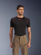 Alpinestars Flex-AST Explorer Hose, Adventure-Motorradhose, Walnut Black, getragen von einem Modell mit schwarzem Base-Layer-Shirt, mit diagonalen Reißverschluss-Cargotaschen und strapazierfähiger Stretch-Textilkonstruktion.