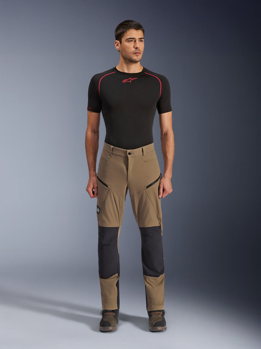 Alpinestars Flex-AST Explorer Hose, Motorrad-Tourenhose, Walnussbraun und Schwarz, mit verstärkten Knieeinsätzen und Oberschenkeltaschen mit Reißverschluss, getragen mit schwarzem kurzärmeligem Baselayer, Ganzkörperansicht