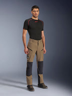 Alpinestars Flex-AST Explorer Hose, Adventure-Motorradhose in Walnut Black, getragen von einem männlichen Model mit schwarzem Kurzarm-Base-Layer und Adventure-Stiefeln, mit Cargotaschen mit Reißverschluss und verstärkten Knieeinsätzen, technische Ausrüstung für Dual-Sport- und Tourenfahrer.