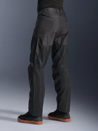 Pantalon Alpinestars C-1 Air, pantalon de moto urbain, noir, vue arrière montrant de larges panneaux en mesh technique à l'arrière des jambes pour la ventilation, style épuré pour la conduite urbaine, porté avec des baskets noires décontractées.