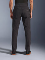 Alpinestars Flex-AST Canvas broek, urban motorbroek, zwart, achteraanzicht met achterzakken voorzien van geborduurd logo, verlengde rugstijging en ergonomische beennaden, gedragen met casual zwart schoeisel