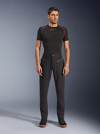 Alpinestars Flex-AST Canvas Pants, urban motorbroek, zwart, gedragen door een model met een zwarte basislaag met korte mouwen en rode stiksels en zwarte casual sneakers, waarbij de voorzakken met ritssluiting en het ergonomische canvas ontwerp worden geaccentueerd.