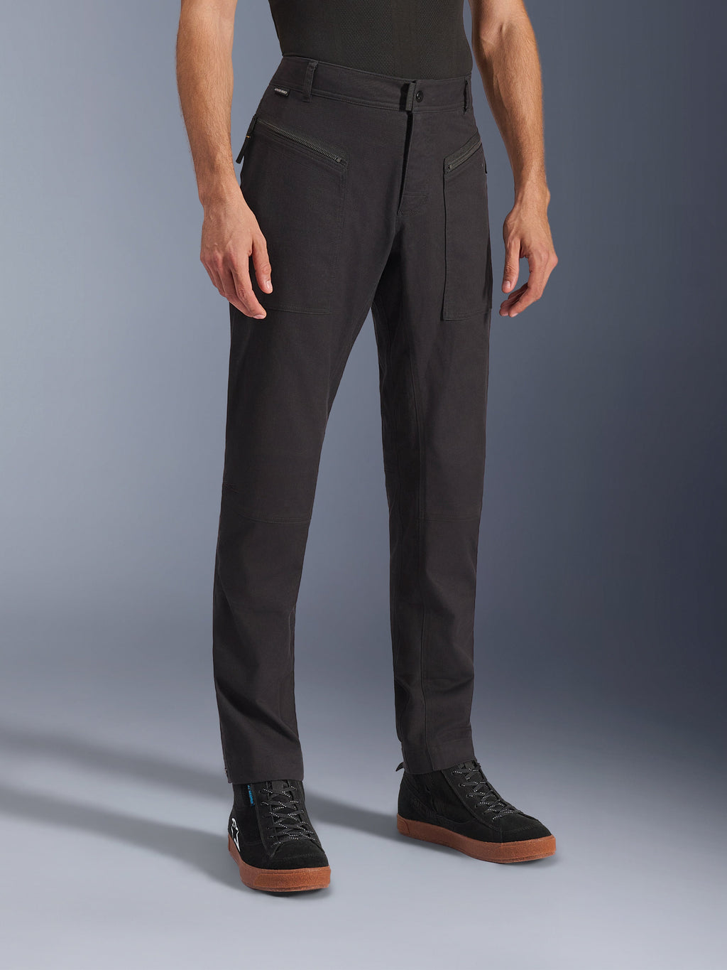 Alpinestars Flex-AST Canvas broek, zwart, urban motorbroek, gedragen door model met zwarte sneakers, met een heritage workwear design, stretch polykatoen twill stof en functionele ritszakken aan de voorzijde.