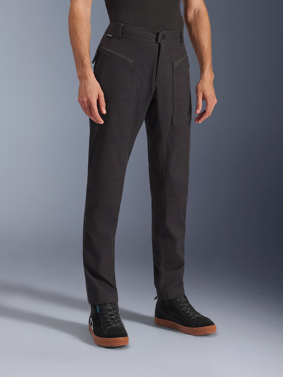 Alpinestars Flex-AST Canvas broek, zwart, urban motorbroek, gedragen door model met zwarte sneakers, met een heritage workwear design, stretch polykatoen twill stof en functionele ritszakken aan de voorzijde.