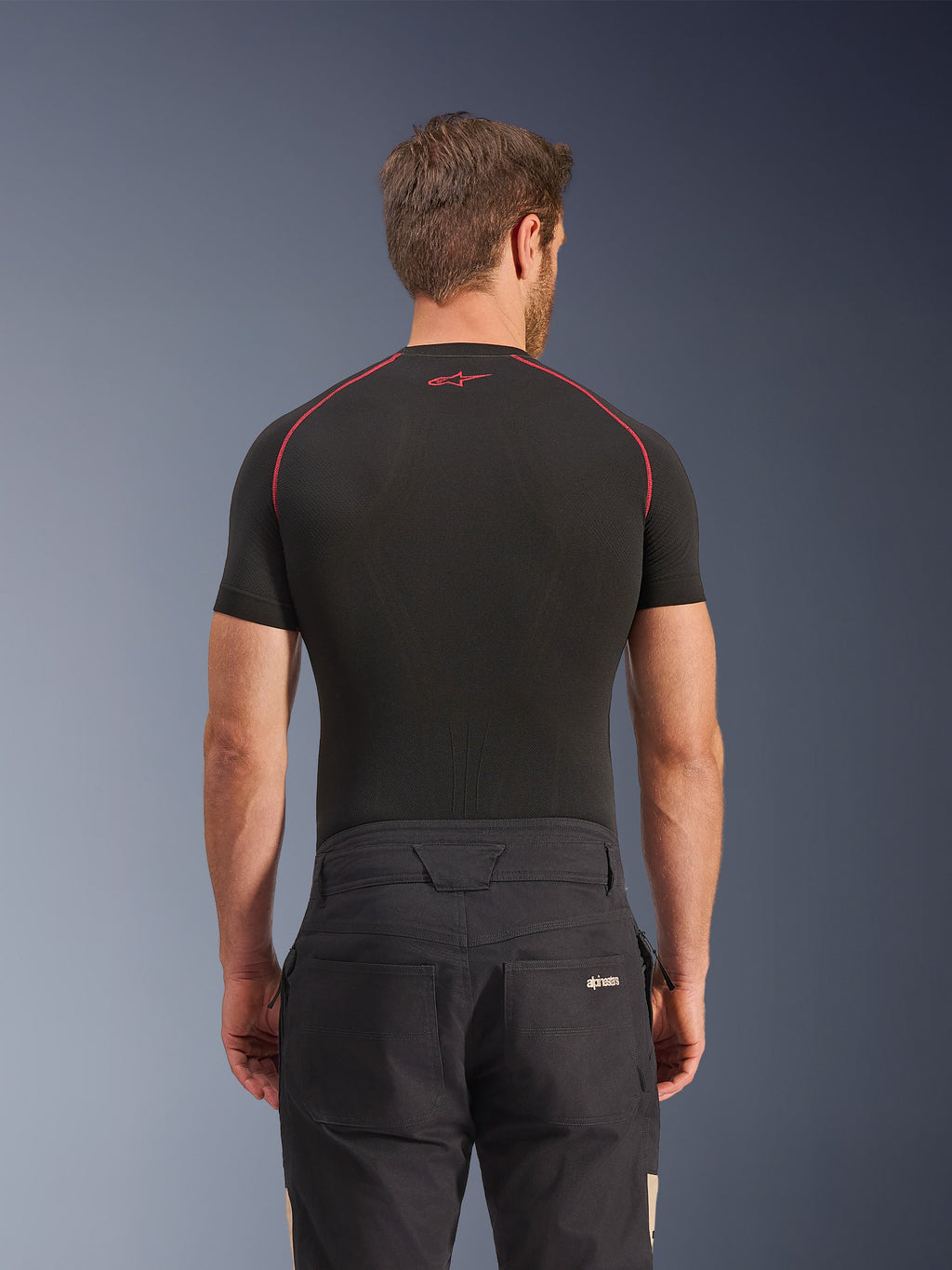 Alpinestars Flex-AST Canvas Pants in Black Aluminum, rear view on model, workwear-inspired urban motorcycle pants with logo on back pocket, paired with a black short-sleeve base layer featuring red stitching.