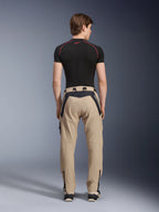 Alpinestars Acteon broek in Sand, moderne urban motorbroek van achteren gezien, voorzien van zwarte panelen met witte Alpinestars-branding, taps toelopende pasvorm met ritsen aan de zoom, gedragen met een zwarte basislaag en sneakers.