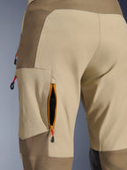 Alpinestars Maxdura Dual Pants in Walnut Aluminum, close-up detail of zippered thigh ventilation vent with orange trim and black mesh, tan and brown heavy-duty stretch polyamide fabric with red pull tabs