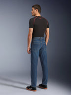 Alpinestars Flex-AST 5 Denim broek, Indigo Washed, achteraanzicht van model dat de broek draagt, urban motorjeans, toelopende pasvorm met monolayer stretchdenim, gecombineerd met een zwart T-shirt en zwarte sneakers