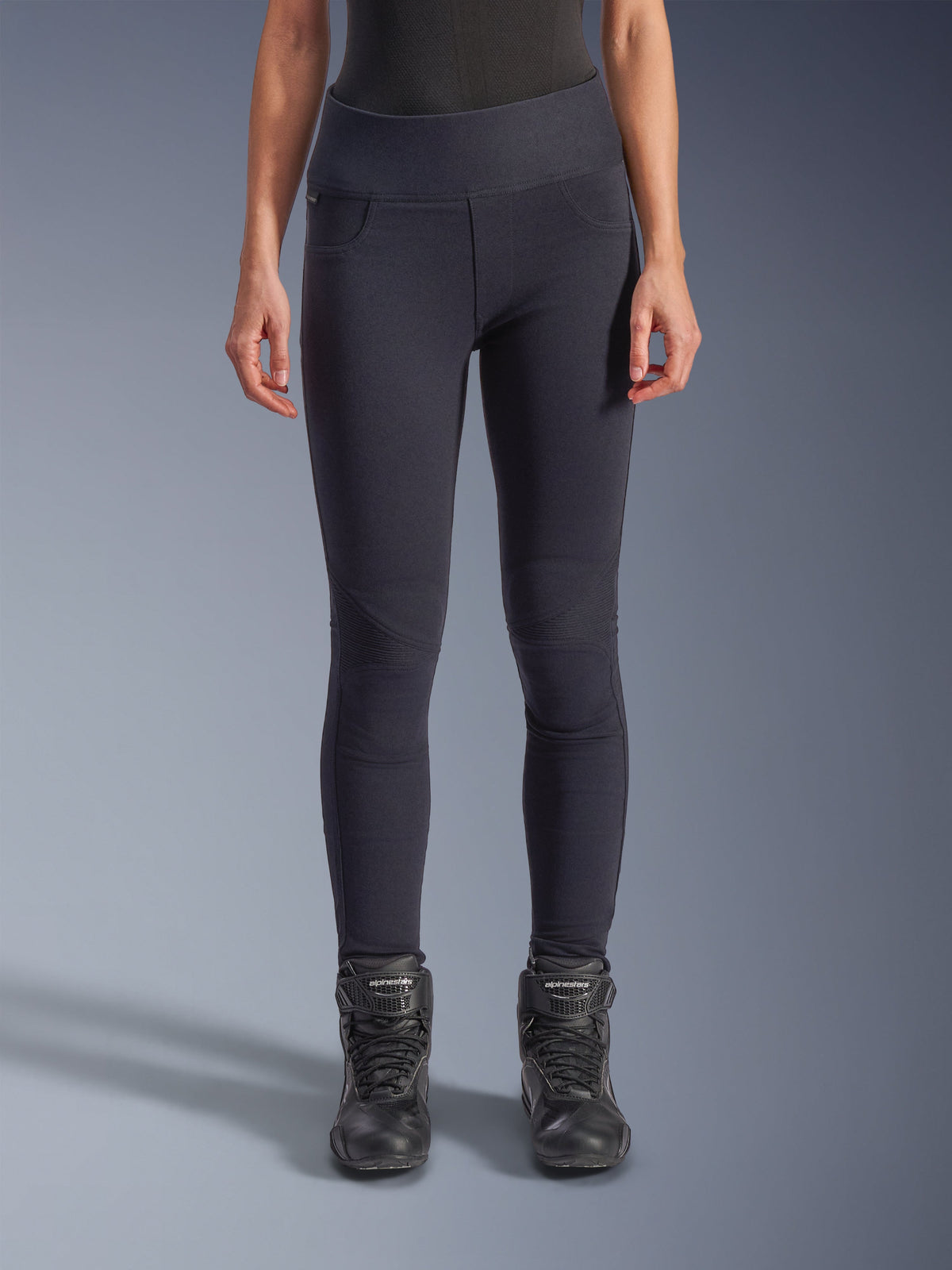 Alpinestars Stella Flex-Ast legging, dames motorlegging, zwart, hoge taille met gearticuleerde kniepanelen en gevormde naden, gedragen door model met zwarte motorlaarzen, urban performance motorkleding