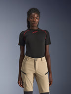 Alpinestars Stella Flex-AST Explorer Pants, Women's motorcycle pants in Sand, worn with a black technical short-sleeve top with red stitching, adventure touring gear featuring zippered cargo pockets and durable ripstop fabric.