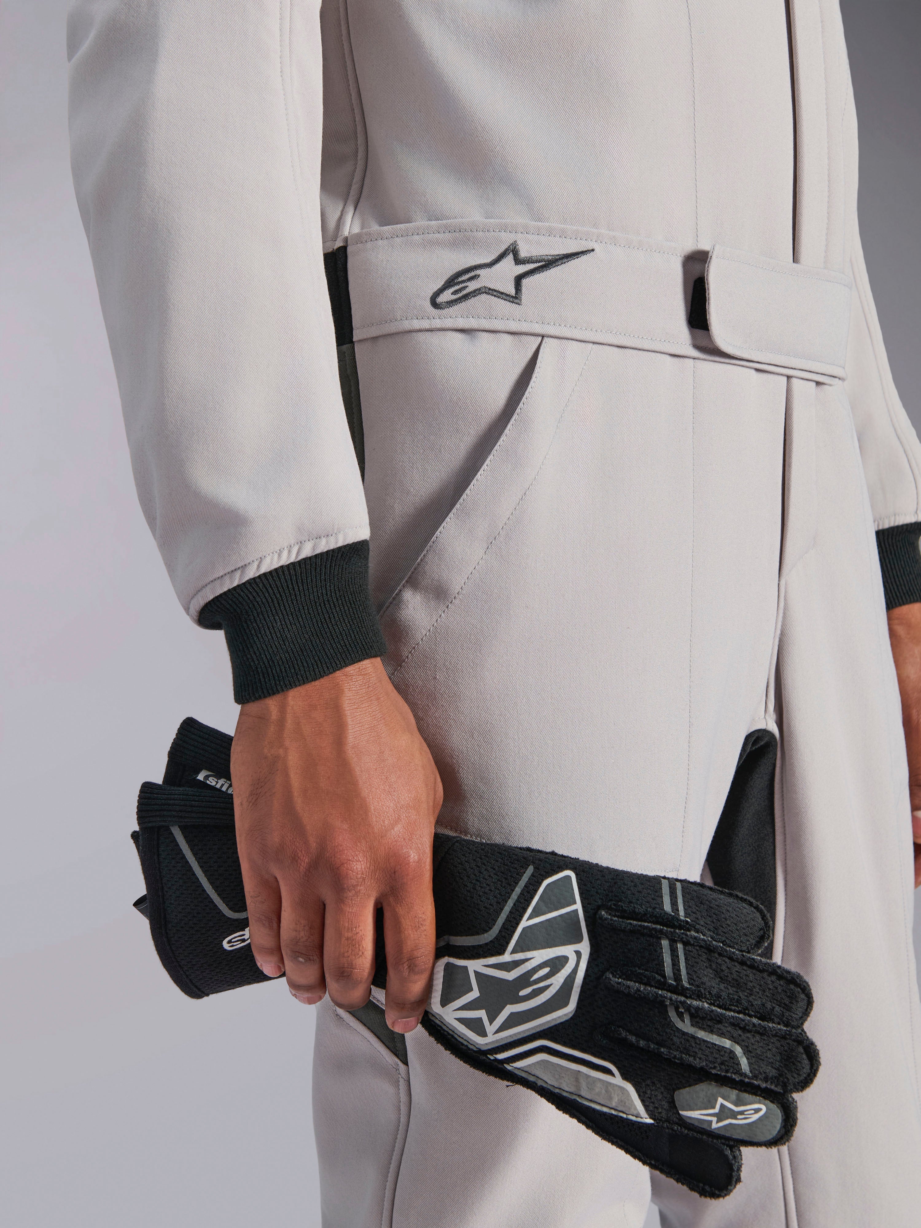 Combinaison Alpinestars GP Race V3 FIA, combinaison de course automobile, Argent Anthracite, tenue avec des gants de course noirs, dotée d'une taille ceinturée ajustable avec logo étoile brodé, poignets côtelés noirs, design sport automobile épuré et professionnel
