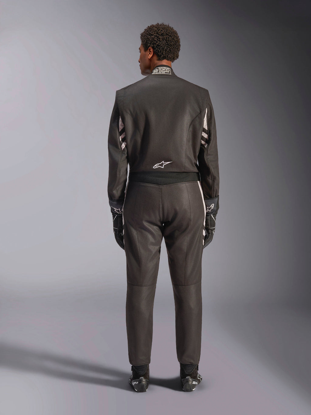 Alpinestars GP Race V3 Suit FIA, vue arrière, noir et argent, combinaison de course automobile professionnelle dotée d'une construction en aramide à deux couches et de panneaux extensibles, portée avec des gants et des bottes de course assortis