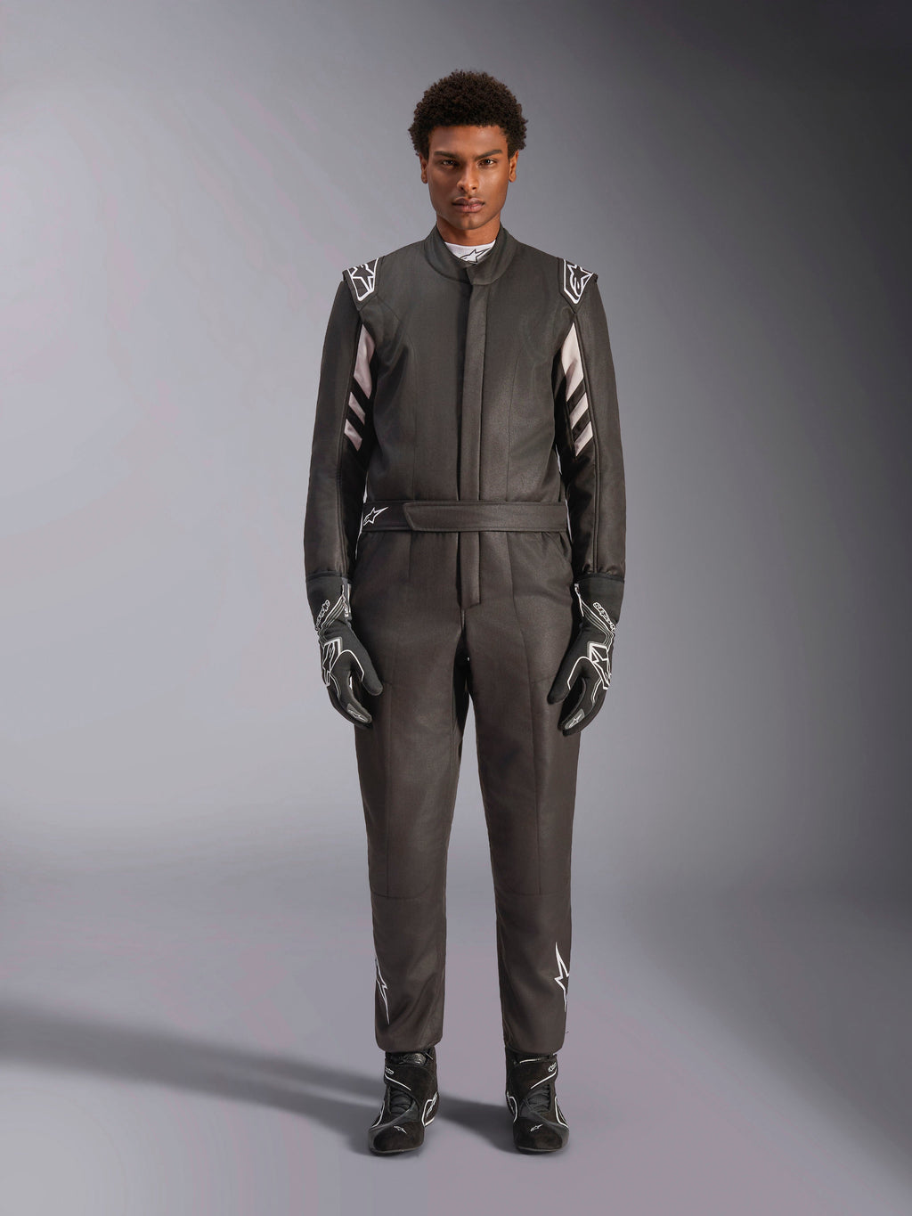 Alpinestars GP Race V3 Suit FIA, combinaison de course automobile, noir et argent, vue de face d'un pilote portant un équipement de course complet incluant gants et bottines, design professionnel de sport automobile avec logos Alpinestars sur les épaules et la ceinture