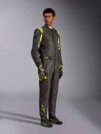 Alpinestars GP Race V3 Suit FIA, autoracepak, zwart met fluoriserend geel, gedragen door een model met bijpassende racehandschoenen en laarzen, voorzien van opvallende gele accenten op de schouders en benen, professionele motorsportuitrusting