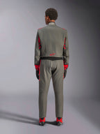 Vue arrière d'un mannequin portant la combinaison Alpinestars GP Race V3 en Anthracite Red, combinaison de course automobile professionnelle avec des accents rouges sur les manches et les jambes, associée à des bottines de course rouges et des gants noirs, équipement technique de sport automobile présenté en studio.