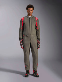 Alpinestars GP Race V3 Anzug FIA, Auto-Rennanzug, Anthrazit-Rot, getragen von einem männlichen Model mit passenden Handschuhen und Stiefeln, mit roten Schulter-Epauletten und Branding, professionelle Motorsportausrüstung für Performance-Fahren.