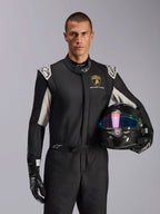 Combinaison Alpinestars GP Tech V4 Édition Limitée Lamborghini, combinaison de course automobile, noir, argent et or, portée par un mannequin tenant un casque en fibre de carbone avec une visière irisée, avec logo Lamborghini Squadra Corse et accents blancs sur les épaules