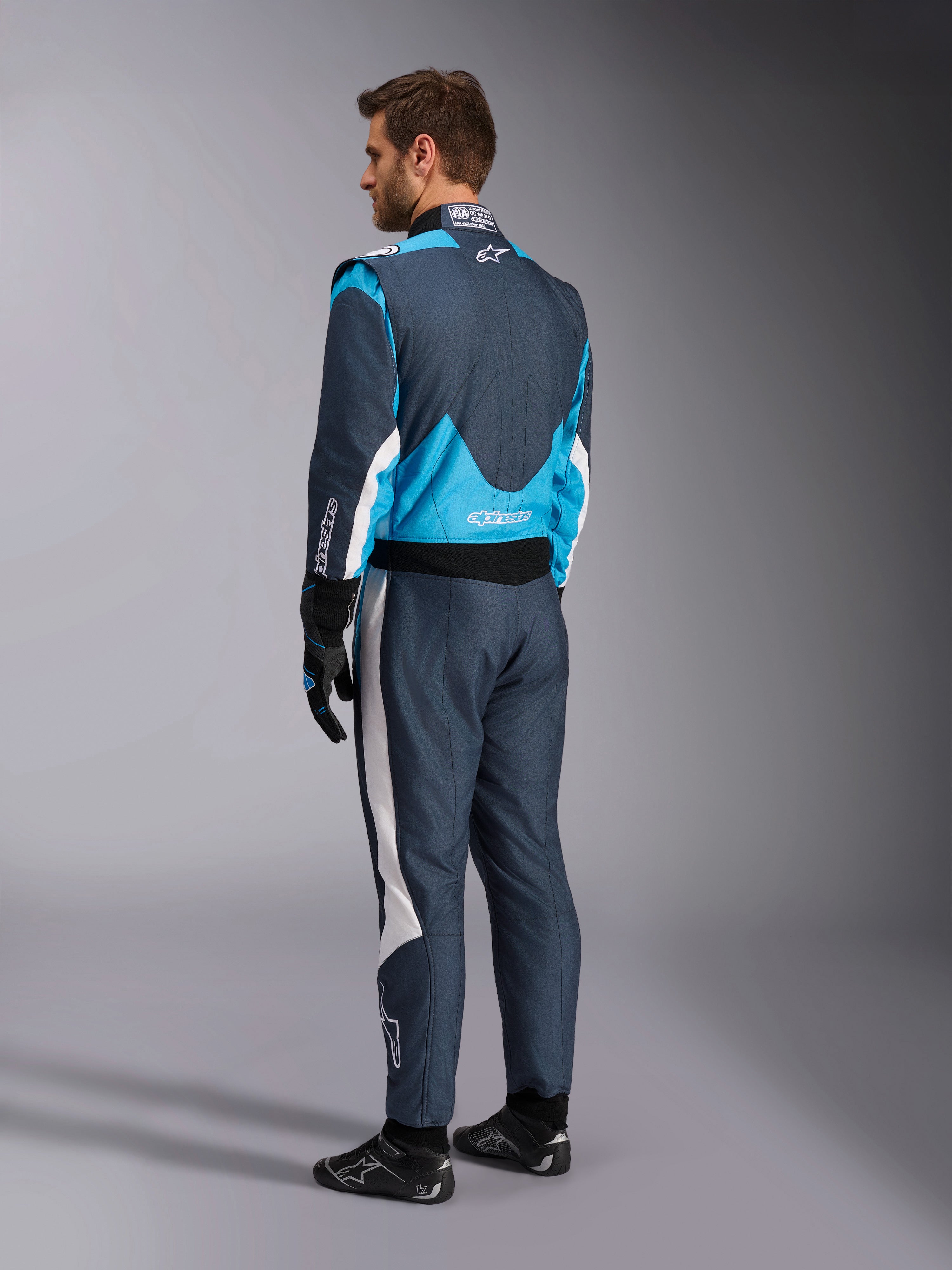 Combinaison Alpinestars GP Pro Comp V2 FIA, combinaison de course, gris asphalte et bleu cyan, vue de dos, mannequin équipé.