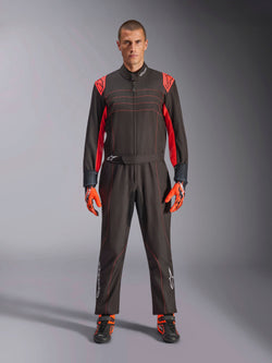 Combinaison de karting Alpinestars KMX-9 V3, noir et rouge fluo, combinaison de course une pièce portée avec des gants et des bottes coordonnés, avec des accents et des surpiqûres rouge vif sur les épaules, logo Alpinestars sur le bas des jambes, design motorsport élégant pour la course sur piste
