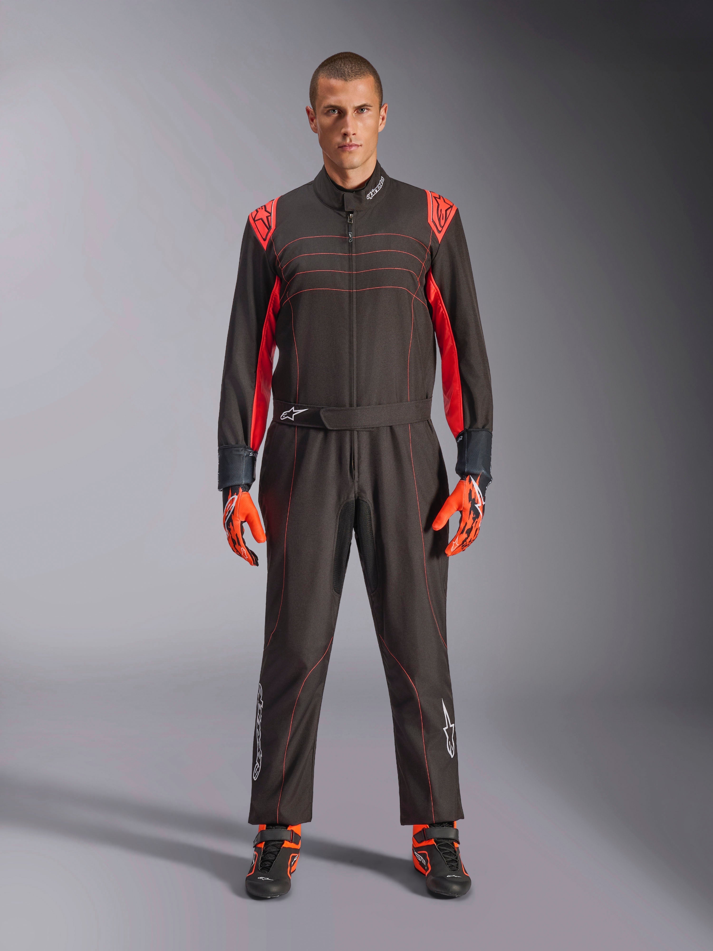 Alpinestars KMX-9 V3 Kart-Anzug, Schwarz und Fluo-Rot, einteiliger Rennanzug getragen mit farblich passenden Handschuhen und Stiefeln, mit leuchtend roten Schulterakzenten und Nähten, Alpinestars-Logo an den Unterschenkeln, schnittiges Motorsport-Design für den Rennsport