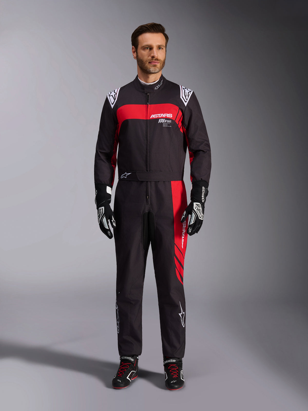 Alpinestars KMX-9 V3 Graphic 3 Suit, Karting Suit, Black and Red, full-body front view worn by a model, featuring bold red graphic panels and white branding, paired with black racing gloves and shoes, professional motorsport apparel.