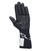 Gants Alpinestars Tech-1 Start V4 FIA, gant de course automobile noir, vue de la paume présentant des motifs d'adhérence en silicone gris sur les doigts et la paume, logo Astars blanc sur la manchette allongée, étiquette d'homologation FIA, équipement de sport automobile professionnel