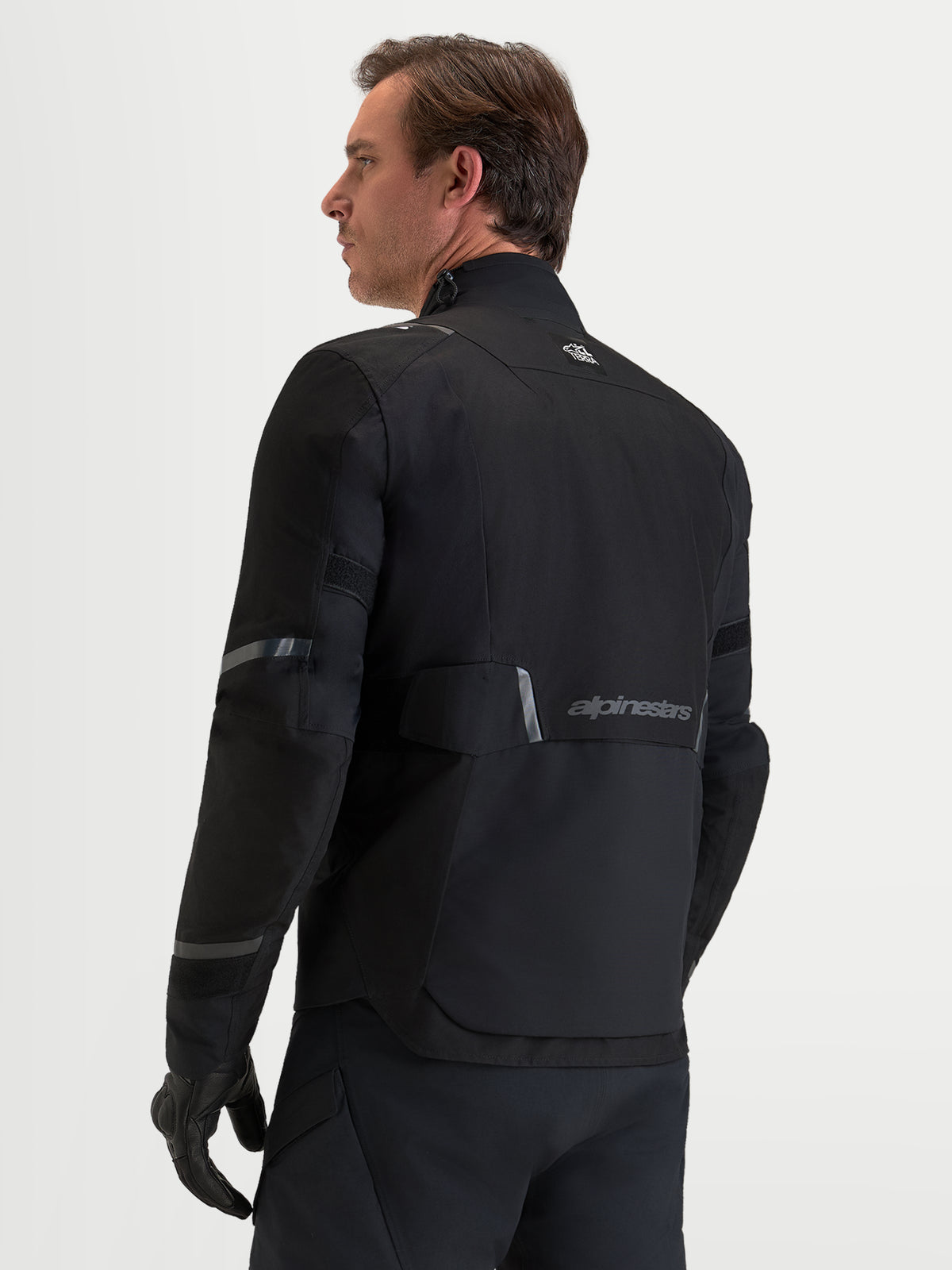 Alpinestars St 7 V 2 2 L Gore Tex Veste, veste de moto adventure pour homme noire, vue de dos montrant la membrane Gore-Tex imperméable, les détails réfléchissants et le marquage Alpinestars