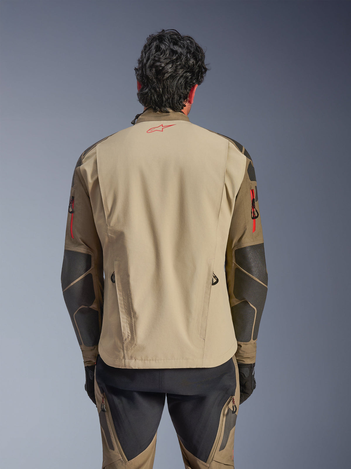 Veste Alpinestars Nazca 3L GORE-TEX PRO, vue de dos, Walnut Rock Brown, veste de moto aventure avec logo Astars rouge sur le col, détails de zips rouges sur les bras et renforts Superfabric aux coudes.