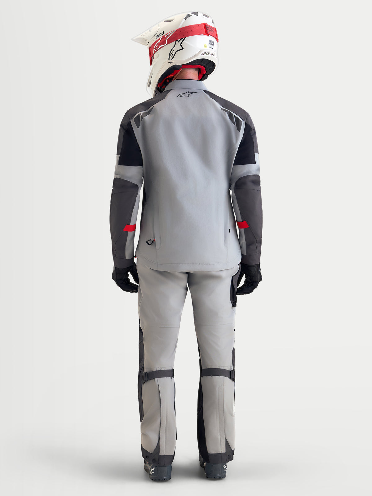 Alpinestars Arenis Gore-Tex jas, heren adventure-motorjas in middengrijs, donkergrijs en zwart, achteraanzicht op model met helm en motoruitrusting