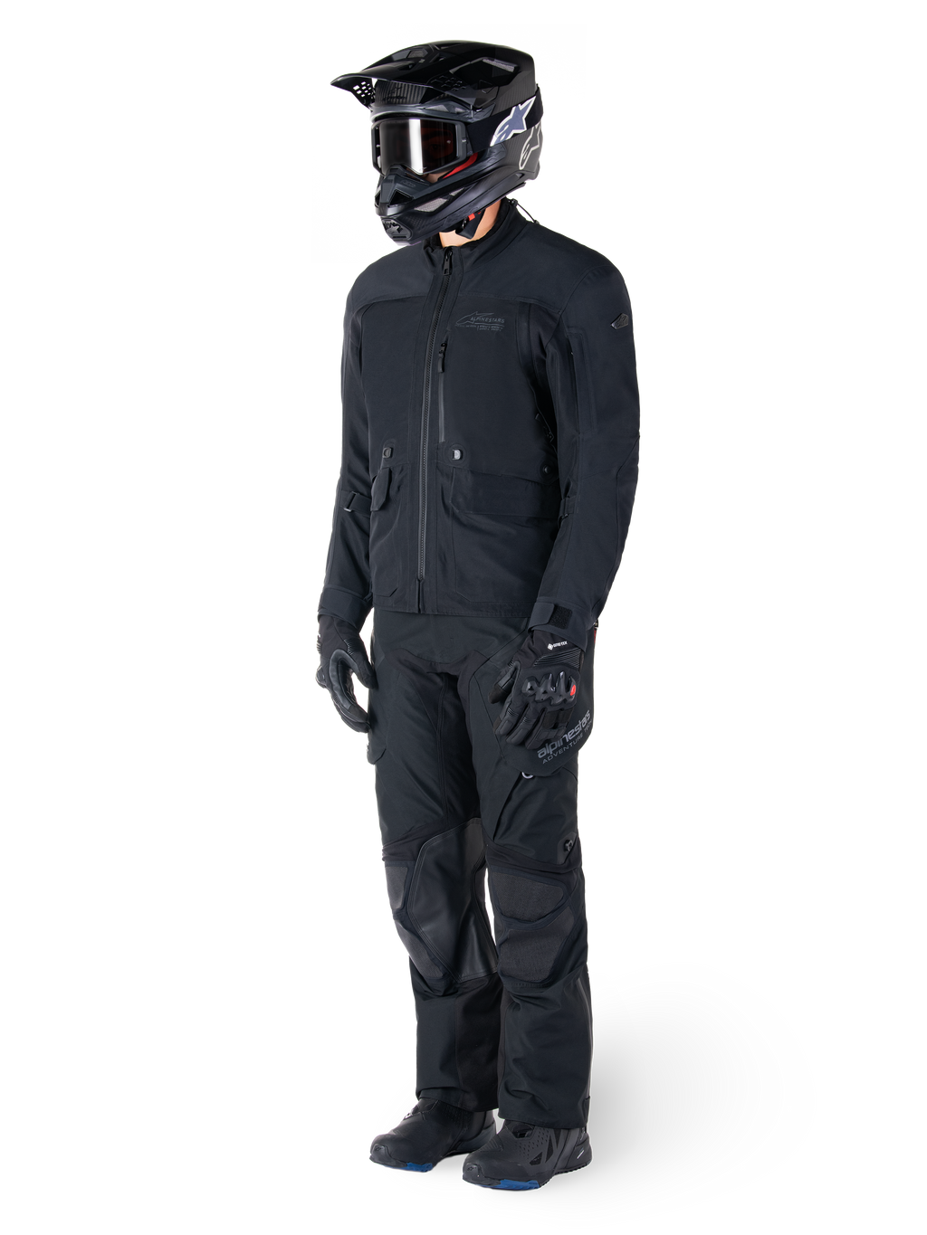 Motorradfahrer in der Alpinestars St-7 Prime GORE-TEX Jacke in Schwarz, abgestimmtes Adventure-Touring-Outfit mit passender schwarzer Hose, schwarzem Helm mit Brille und Handschuhen, schlankes und funktionales Design für Allwetter-Performance.