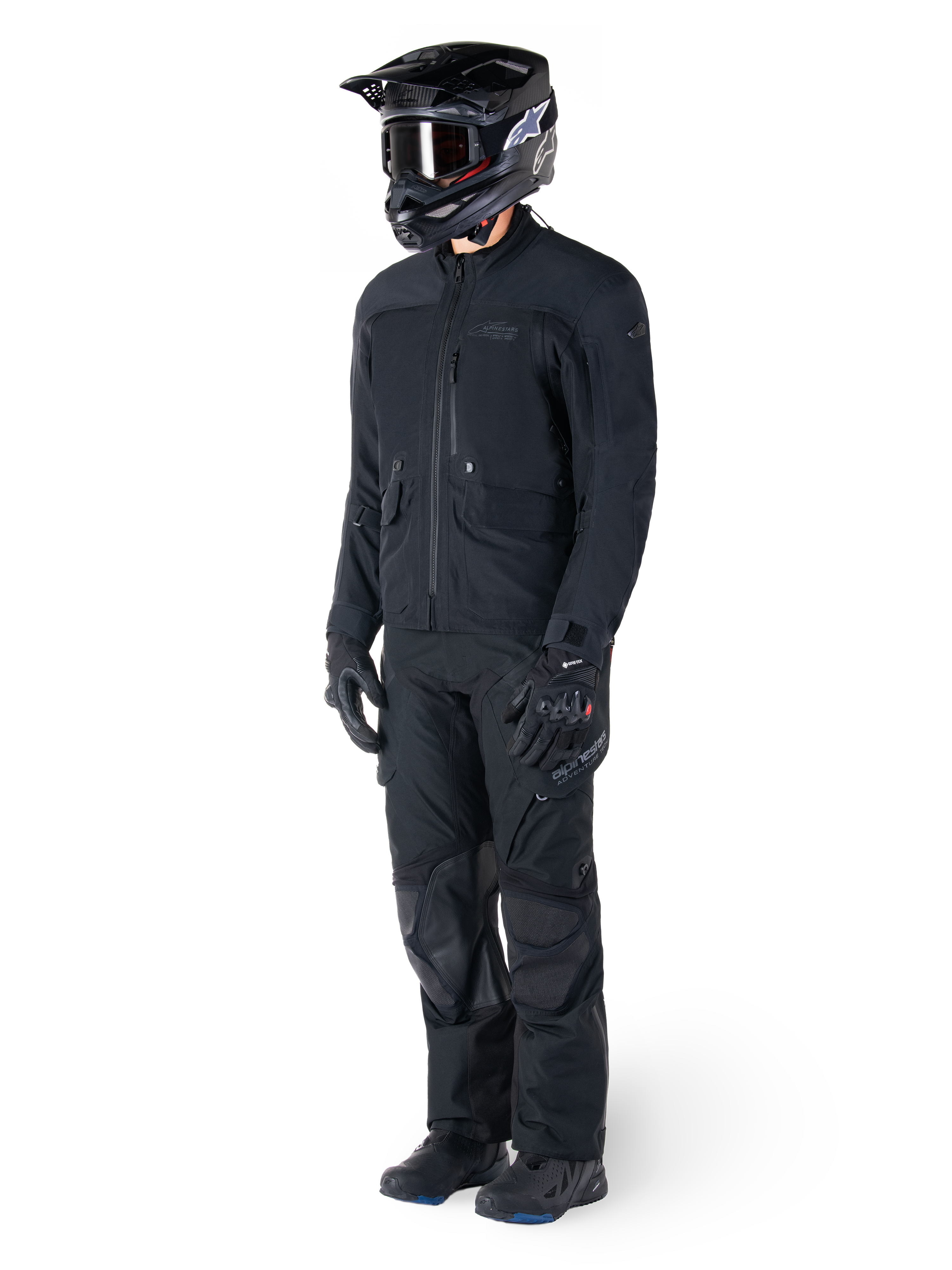 Motorradfahrer in der Alpinestars St-7 Prime GORE-TEX Jacke in Schwarz, abgestimmtes Adventure-Touring-Outfit mit passender schwarzer Hose, schwarzem Helm mit Brille und Handschuhen, schlankes und funktionales Design für Allwetter-Performance.