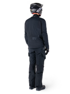 Rückansicht eines Fahrers mit der Alpinestars St-7 Prime GORE-TEX Jacke in Schwarz, kombiniert mit einer passenden schwarzen Tourenhose, einem schwarzen Motorradhelm mit weißem Logo und schwarzen Motorradstiefeln, komplette Adventure-Schutzausrüstung für Touren und Pendelfahrten.