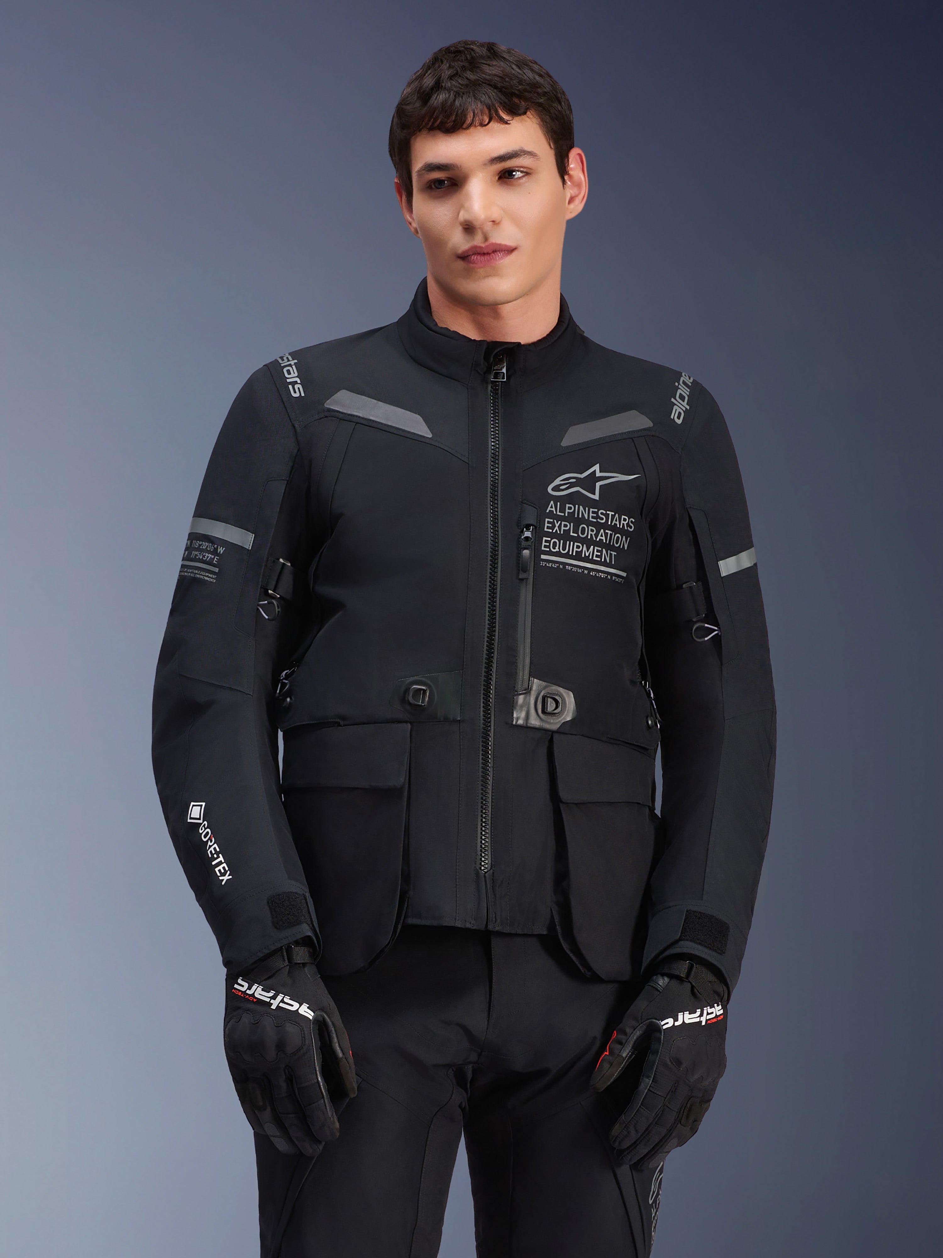 Alpinestars ST-7 2L GORE-TEX Jacke, Motorrad-Tourenjacke, Schwarz und Dunkelgrau, mit Alpinestars Exploration Equipment Branding auf der Brust, großen wasserdichten Cargo-Taschen, GORE-TEX Logo am Ärmel, robustes abenteuertaugliches Design mit reflektierenden Akzenten