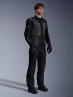Mannelijk model in de Alpinestars ST-7 2L GORE-TEX Jas in Deep Gray Black en Dark Khaki, gecombineerd met bijpassende zwarte adventure-broek en handschoenen, voorzien van een waterdichte gelamineerde buitenlaag met cargozakken en technische branding, ideaal voor adventure touring.