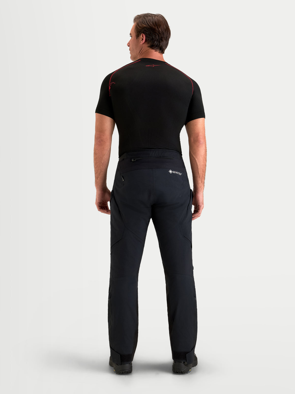 Alpinestars St 7 V 2 2 L Gore Tex Pantalons, pantalon de moto adventure pour homme noir, vue de dos sur un modèle montrant la construction textile imperméable et le marquage GORE-TEX