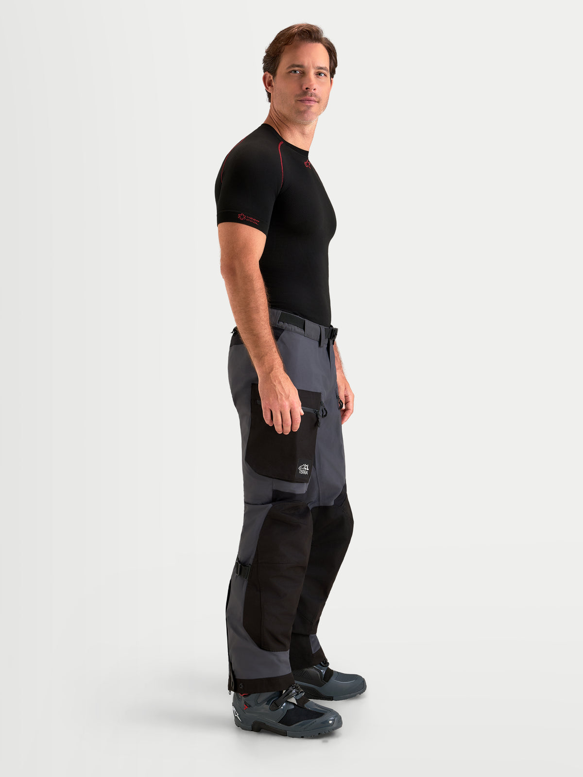 Alpinestars Arenis Gore-Tex Pantalons, pantalon de moto adventure pour homme noir et gris foncé, vue de profil de côté porté par un modèle montrant la construction textile imperméable et la poche cargo