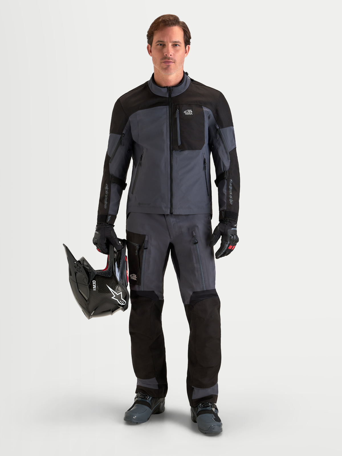Alpinestars Arenis Gore-Tex Pantalons, pantalon de moto adventure pour homme noir et gris foncé, vue de face sur un modèle portant un équipement assorti, un casque et une tenue de protection imperméable