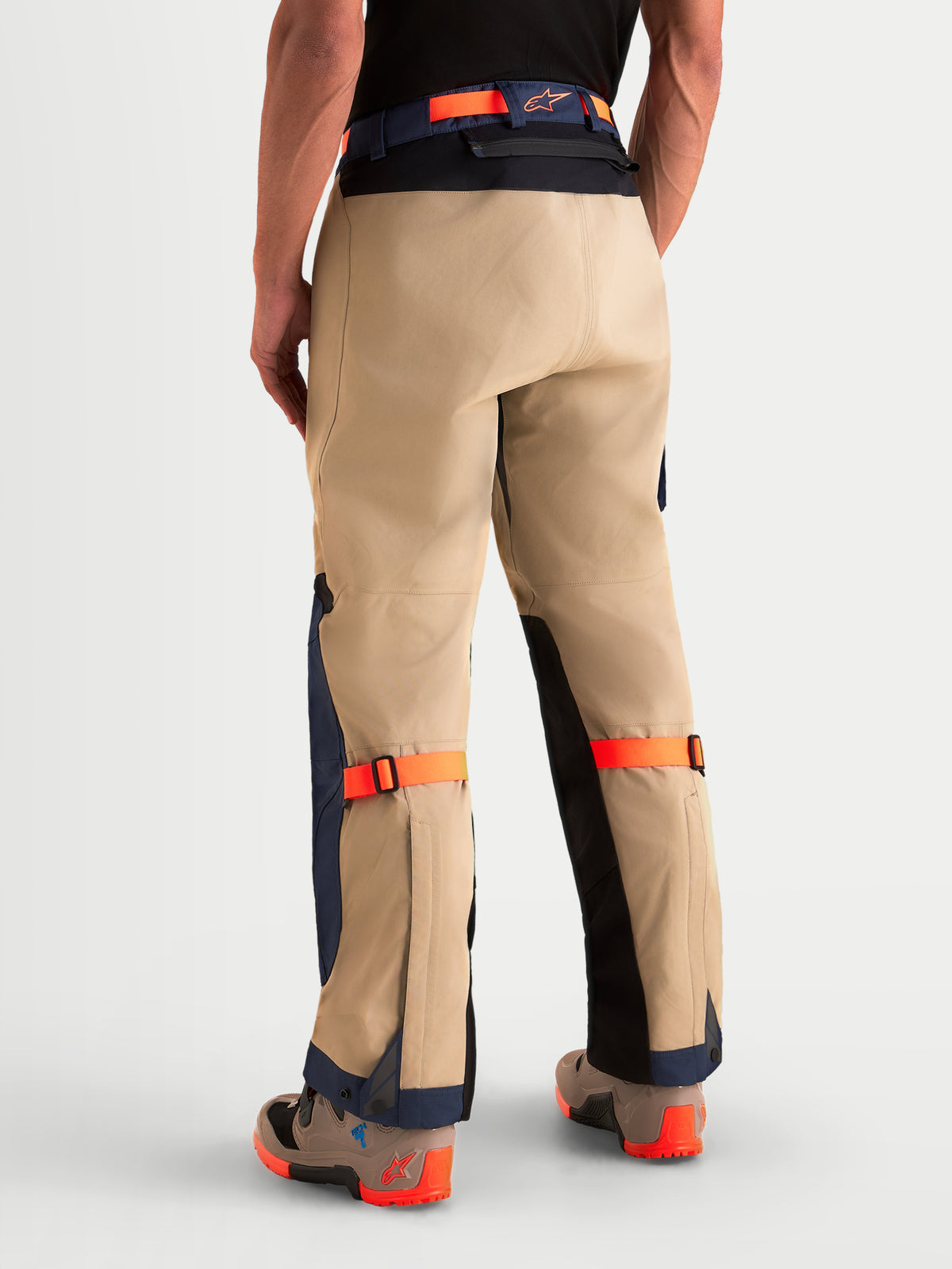 Alpinestars Pantalon Arenis Gore-Tex, pantalon de moto adventure pour homme beige, bleu marine et orange, vue de dos sur un modèle avec construction textile imperméable et sangles de réglage