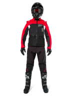 Motorcrosser in complete off-road uitrusting, Alpinestars Pro-Dura jas in zwart, felrood en wit, zwarte broek met rode accenten, zwarte helm met rode crossbril, zwart-witte laarzen, gecoördineerde outfit voor enduro- en trailrijden