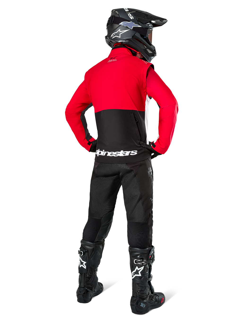 Motocrossrijder van achteren gezien, dragend de Alpinestars Pro-Dura jas in zwart, felrood en wit, gecombineerd met een zwarte broek, zwarte helm en zwarte off-road laarzen, met een rood bovenstuk en een zwart onderstuk met witte Alpinestars-logo's op de rug.