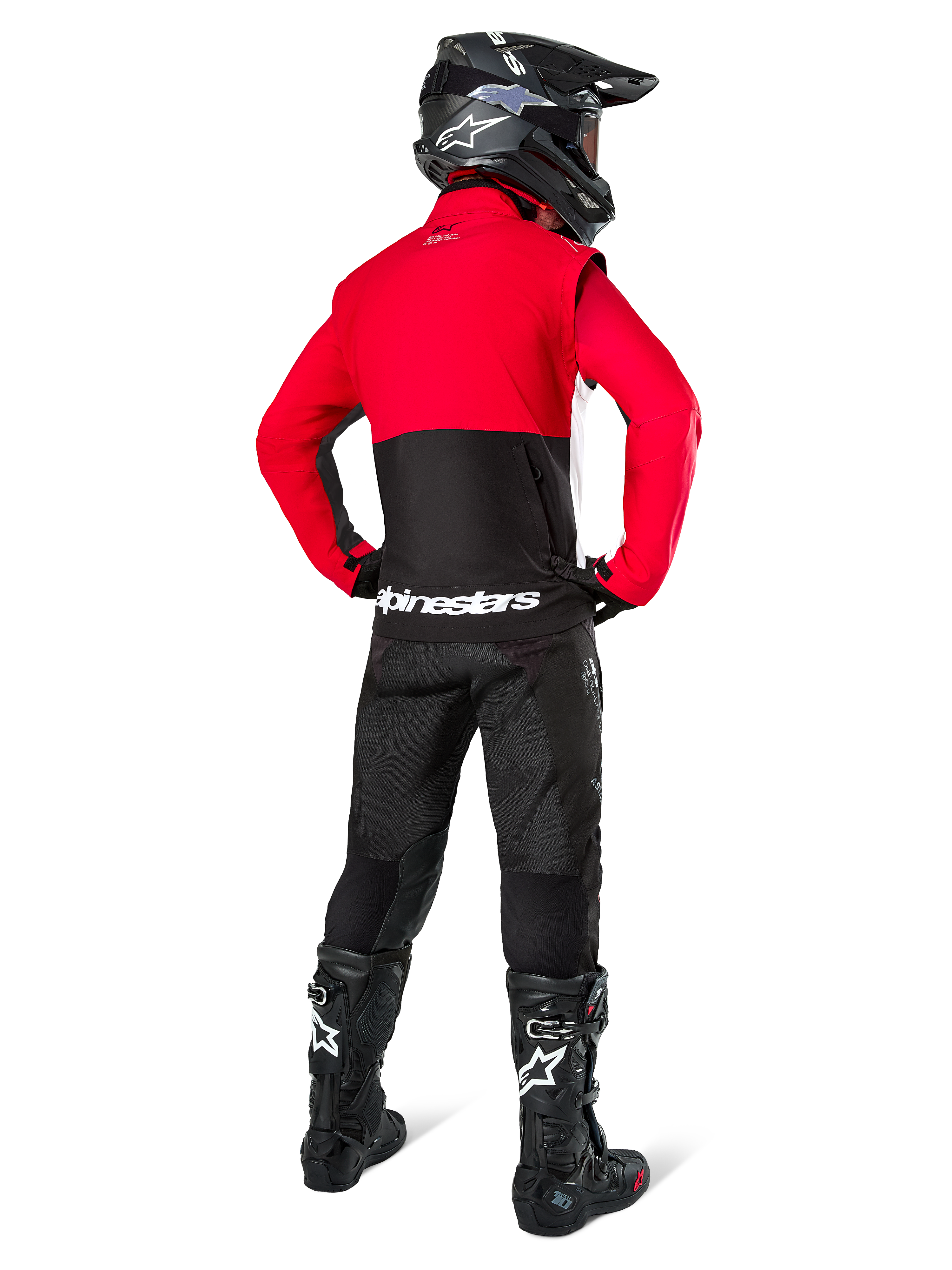 Motocrossrijder van achteren gezien, dragend de Alpinestars Pro-Dura jas in zwart, felrood en wit, gecombineerd met een zwarte broek, zwarte helm en zwarte off-road laarzen, met een rood bovenstuk en een zwart onderstuk met witte Alpinestars-logo's op de rug.