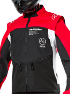 Alpinestars Pro-Dura jas, off-road motorjas, zwart, felrood en wit, gedragen met een zwarte helm, voorzien van zakken met ritssluiting en opvallende branding op de borst, duurzame textielconstructie voor enduro- en trailrijden
