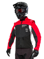 Alpinestars Pro-Dura Jacket, off-road enduro motorjas, zwart met felrood en wit kleurontwerp, gedragen door een rijder met een zwarte helm en crossbril, voorzien van ritszakken aan de voorzijde en Alpinestars-branding, duurzame textielconstructie voor trailrijden