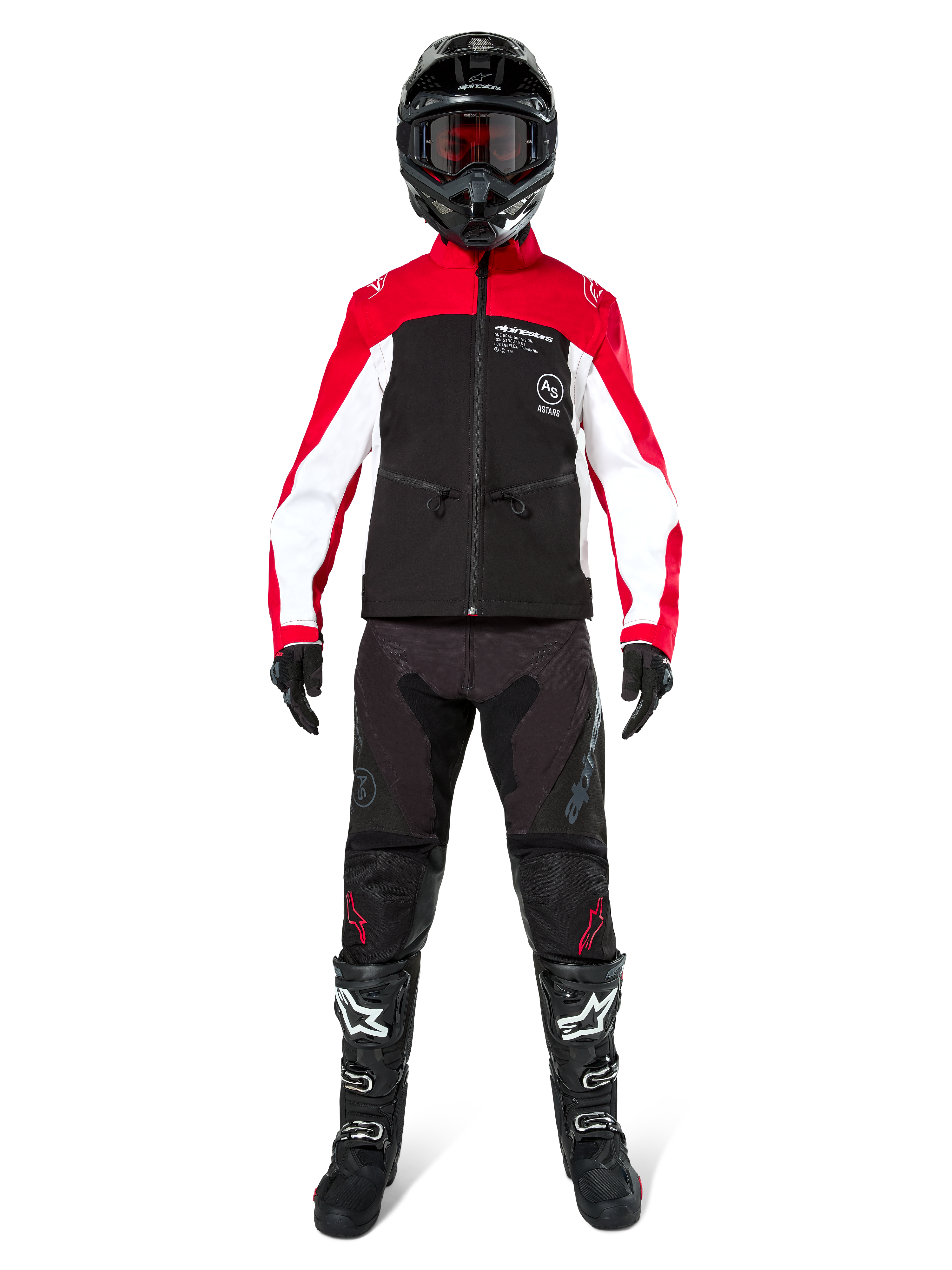 Pilote de motocross portant la veste Softshell Alpinestars Lite-Dura en noir, rouge vif et blanc, coordonnée avec un pantalon tout-terrain noir, des bottes noires et blanches et un casque noir avec lunettes, tenue complète pour la course d'enduro