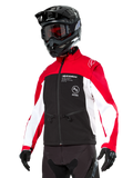 Veste softshell Alpinestars Lite-Dura, veste de moto, noir, rouge vif et blanc, portée par un pilote avec casque de motocross noir, lunettes rouges et gants, logo distinctif sur la poitrine, conçue pour le tout-terrain et l'enduro