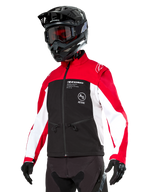 Veste softshell Alpinestars Lite-Dura, veste de moto, noir, rouge vif et blanc, portée par un pilote avec casque de motocross noir, lunettes rouges et gants, logo distinctif sur la poitrine, conçue pour le tout-terrain et l'enduro
