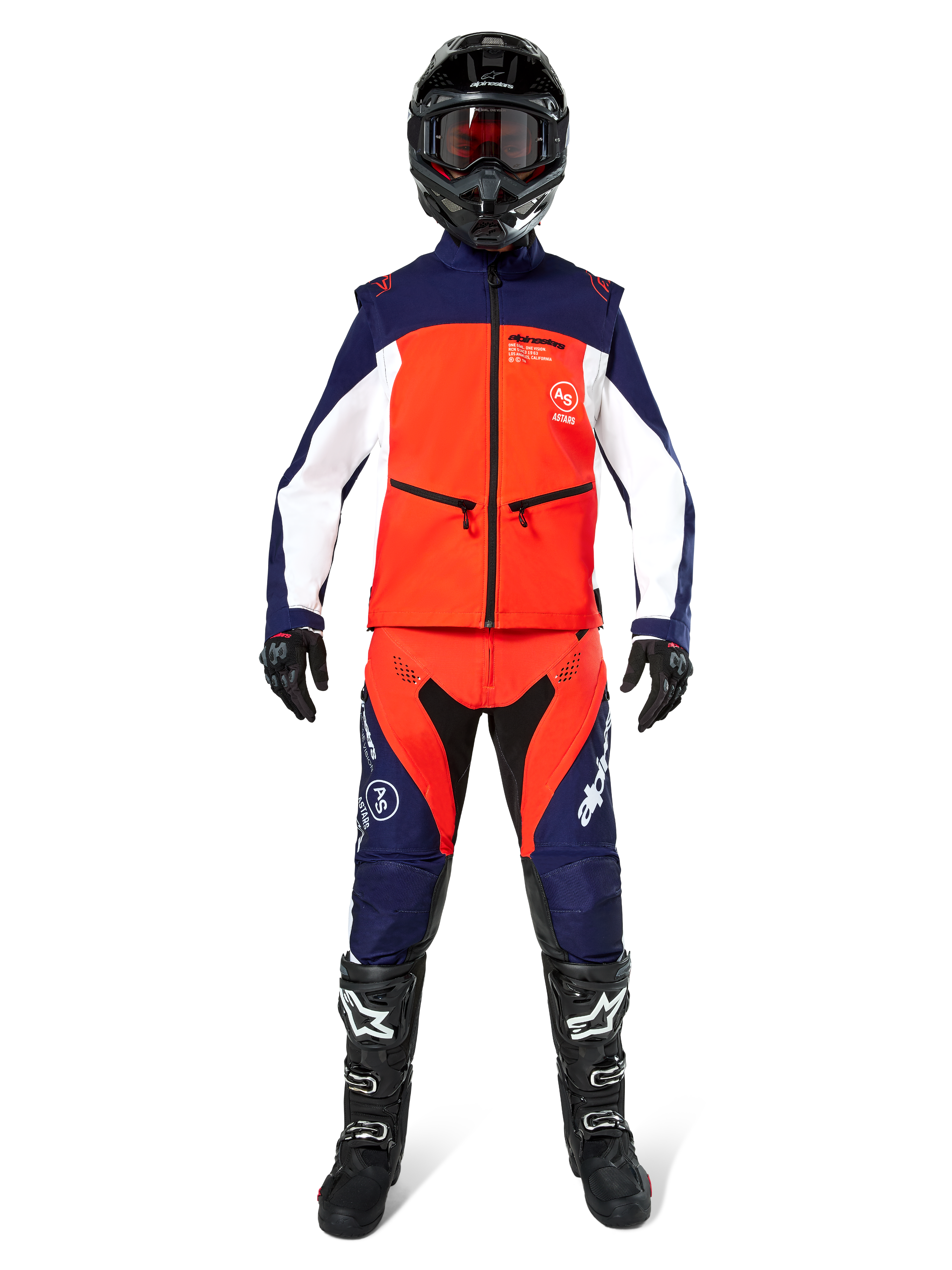 Pilote de motocross portant un équipement tout-terrain complet, veste Softshell Lite-Dura Alpinestars en bleu marine, orange vif et blanc, pantalon assorti marine et orange, casque noir avec lunettes, bottes noires et blanches, gants noirs, tenue coordonnée pour la course d'enduro.