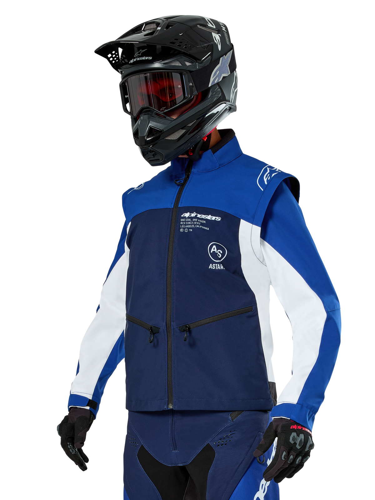 Alpinestars Lite-Dura Softshell-Jacke, Navy, Hellblau und Weiß, Offroad-Enduro-Jacke, getragen mit schwarzem Helm und rot getönter Brille, sportliches Color-Block-Design mit mehreren Reißverschlüssen und Markenlogos, strapazierfähiges Textil für Motocross und Trail-Fahrten