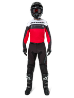Motocross-Fahrer in Alpinestars Pro-Dura Hose in Schwarz und Magnet, kombiniert mit einem rot-weiß-schwarzen Trikot, schwarzem Helm und schwarzen Stiefeln, komplette Offroad-Rennausrüstung, strapazierfähiges und leichtes Design für Enduro-Fahrten